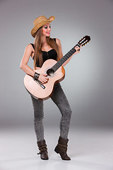 Image showing The beautiful girl in a cowboy\'s hat and acoustic guitar.