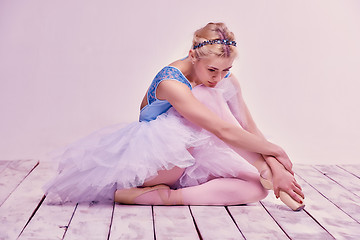 Image showing Tired ballet dancer sitting on the wooden floor 