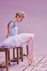 Image showing Tired ballet dancer sitting on the wooden floor 