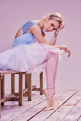 Image showing Tired ballet dancer sitting on the wooden floor 