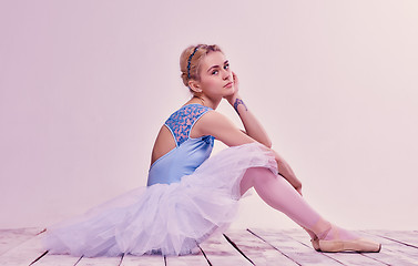 Image showing Tired ballet dancer sitting on the wooden floor 
