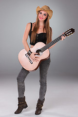 Image showing The beautiful girl in a cowboy\'s hat and acoustic guitar.