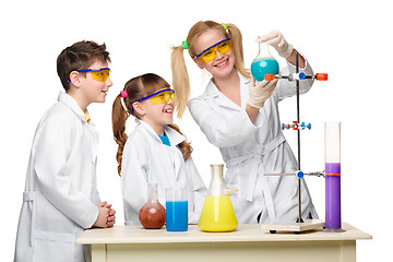 Image showing Teens and teacher of chemistry at  lesson making experiments