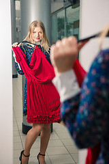Image showing Woman trying red dress shopping for clothing. 