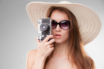 Image showing Girl in broad-brimmed hat  and sunglasses with retro camera 