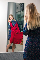 Image showing Woman trying red dress shopping for clothing. 