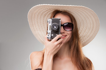 Image showing Girl in broad-brimmed hat  and sunglasses with retro camera 