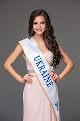 Image showing Beautiful young brunette woman with her hair posing in a i pink dress. Studio, on gray background