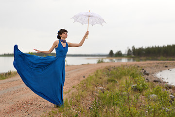 Image showing A girl tries to keep a umbrella which pulls out a wind