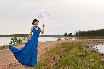 Image showing A girl tries to keep a umbrella which pulls out a wind.