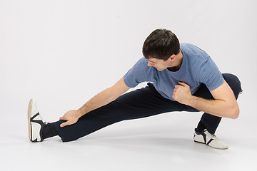 Image showing Athlete crouching pulling muscles of the right leg