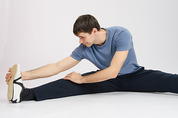 Image showing Athlete in training stretches the muscles of right leg