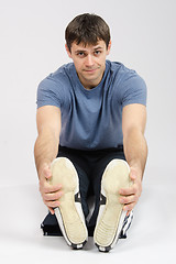 Image showing The young man stretches muscles of legs