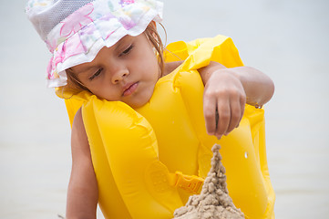 Image showing Five-year girl builds a sand castle