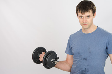 Image showing Athlete pumps muscle of the right hand using dumbbells