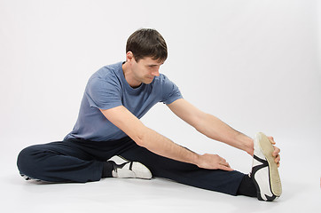 Image showing The young man stretches muscles of left leg