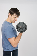 Image showing Athlete looks at arm muscles under weight of dumbbell