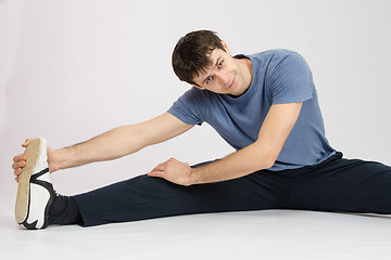 Image showing Man in training stretches muscles of the right leg