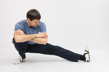 Image showing Athlete crouching stretches muscles of left leg