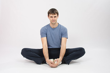 Image showing Athlete sitting holding hands your feet