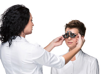 Image showing Optometrist holding an eye test glasses and giving to young woman examination