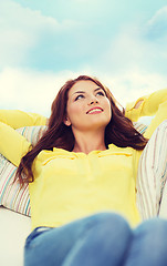 Image showing smiling young woman lying on sofa at home