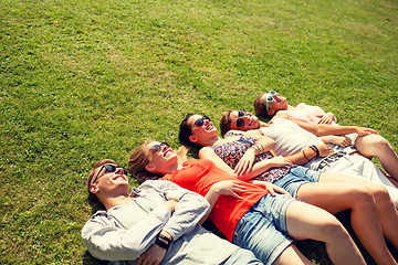 Image showing group of smiling friends lying on grass outdoors