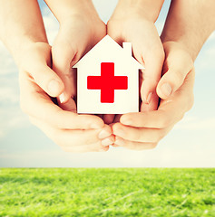 Image showing hands holding paper house with red cross