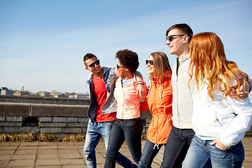 Image showing happy teenage friends walking along city street