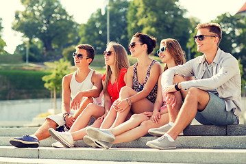 Image showing group of smiling friends sitting on city square