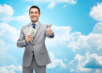 Image showing smiling businessman with money showing thumbs up