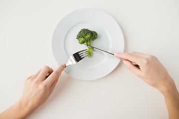 Image showing close up of woman hands eating broccoli