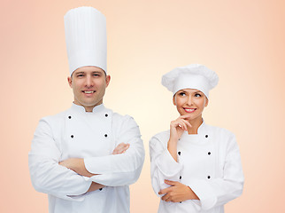 Image showing happy chefs or cooks couple over beige background