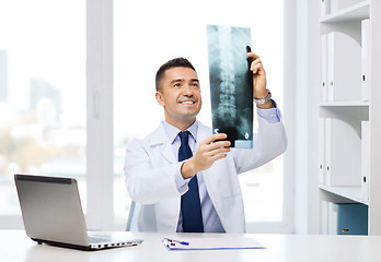 Image showing smiling male doctor in white coat looking at x-ray
