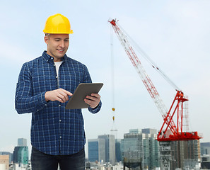 Image showing smiling male builder in helmet with tablet pc