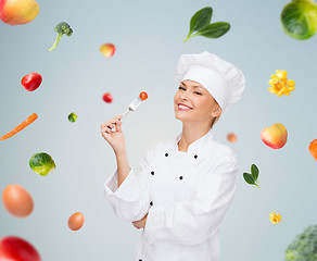 Image showing smiling female chef with fork and tomato