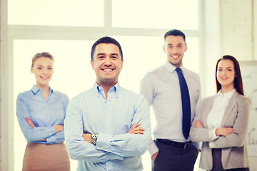 Image showing smiling businessman in office with team on back