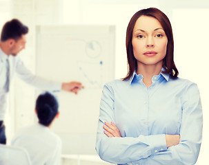 Image showing smiling businesswoman with crossed arms at office