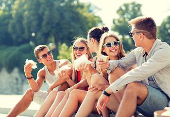 Image showing group of smiling friends sitting on city square