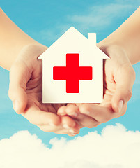 Image showing hands holding paper house with red cross