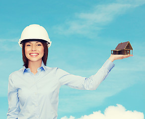 Image showing businesswoman in helmet holding house on palm