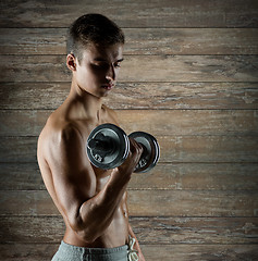 Image showing young man with dumbbell flexing biceps