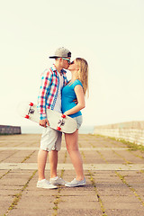 Image showing smiling couple with skateboard kissing outdoors