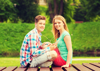 Image showing smiling couple with smartphone and earphones