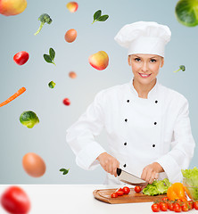 Image showing smiling female chef chopping vegetables