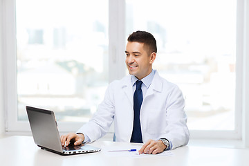 Image showing smiling male doctor with laptop in medical office