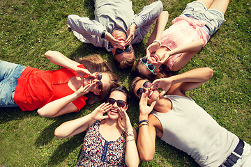 Image showing group of smiling friends lying on grass outdoors