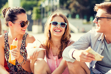 Image showing group of smiling friends sitting on city square