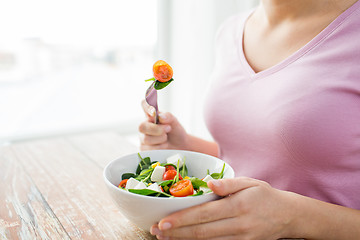 Image showing close up of young woman eating salad at home