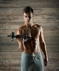 Image showing young man with dumbbell flexing biceps